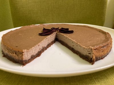 Rozkrojený kakaový cheesecake, servírovaný na bílém talíři
