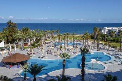 Resort s bazény, palmami a lehátky, v pozadí moře