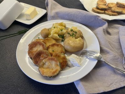 Smažená cuketa s bramborami, servírovaná na bílém talíři