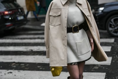 Žena v šedém outfitu s šaty přepásanými výrazným černým páskem