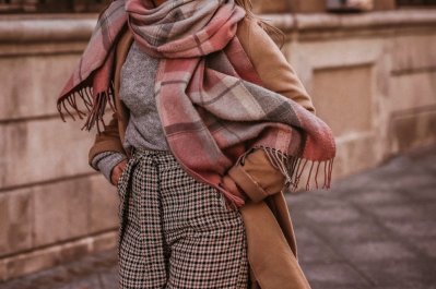 Žena v outfitu v neutrálních barvách s kostkovanou šálou okolo krku