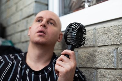 Muž drží v ruce malý ruční ventilár.