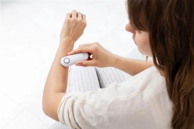 Žena si ošetřuje štípanec bílým klikacím přístrojem.