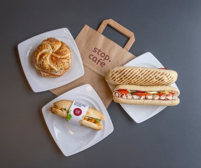 Plněné pečivo na bílých talířích a papírová taška s logem Stop Cafe