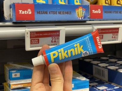 Ruka držící kondenzované mléko Piknik v tubě v supermarketu