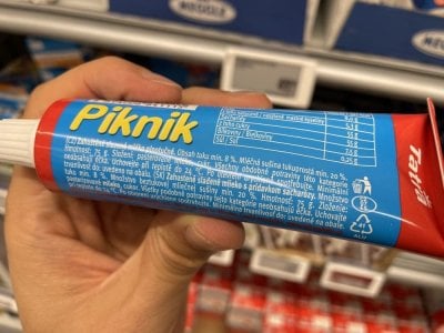 Ruka držící kondenzované mléko Piknik v tubě v supermarketu