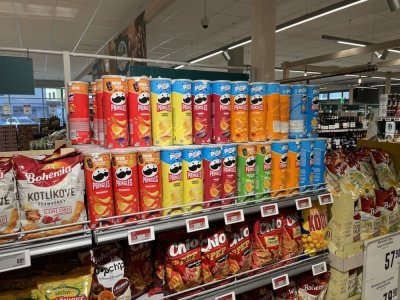 Pringles a další slané pochutiny v regálu supermarketu