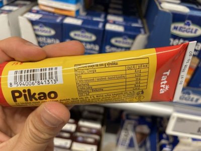 Ruka držící kondenzované mléko Pikao v tubě v supermarketu
