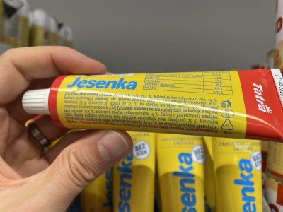 Ruka držící kondenzované mléko Jesenka v tubě v supermarketu