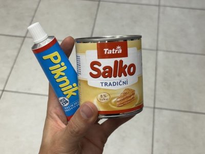 Ruka držící kondenzovaná mléka Piknik a Salko