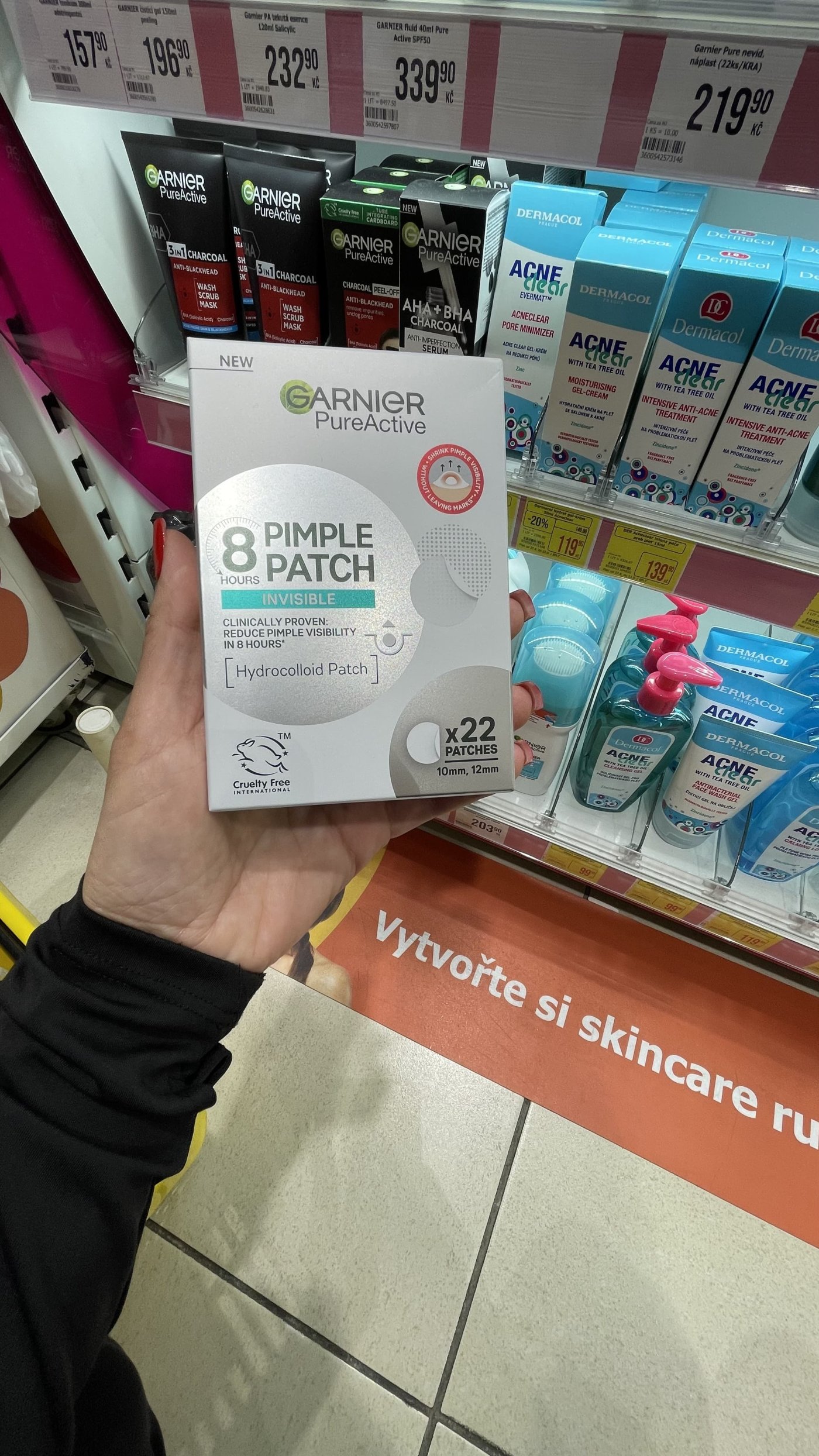 Ženská ruka drží v drogerii náplasti na akné v produktovém obalu