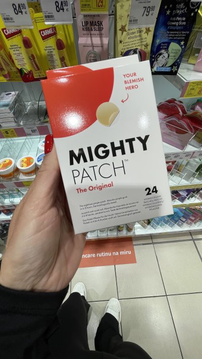 Ženská ruka drží v drogerii náplasti na akné v produktovém obalu