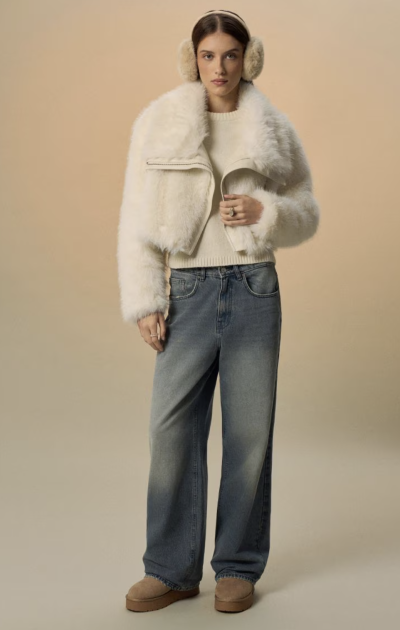Modelka v bílé bundě z umělé kožešiny a džínách