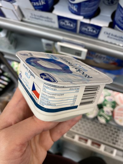 Ruka držící řecký jogurt v supermarketu
