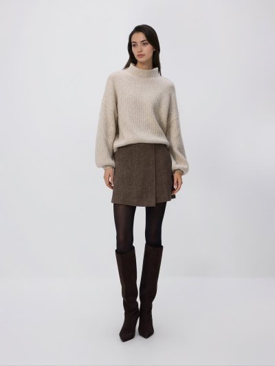 Žena v sukni a béžovém svetru