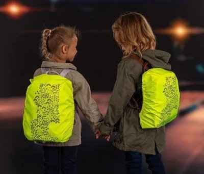Dvě děti s batohem na zádech pokrytým reflexním obalem