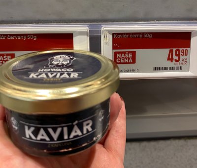 Ruka držící produkt Nowaco Kaviár z kapelina severního před regálem supermarketu