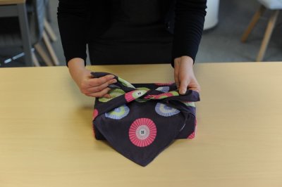 Žena balí dárek do čtvercového šátku