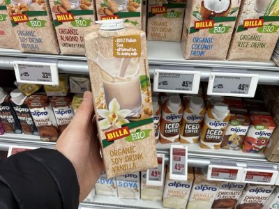 Ruka držící balení rostlinného mléka před regálem supermarketu