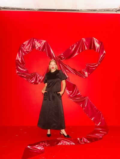 Žena v černé saténové sukni a topu na červeném pozadí