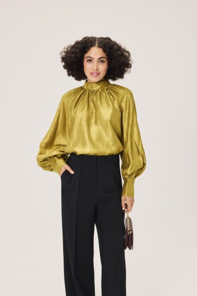 Modelka v černých kalhotách a zlaté blůze