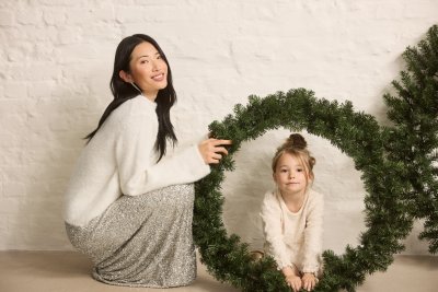 Žena v bílém svetru a stříbrné sukni, malá dívka v bílé halence, vánoční věnec