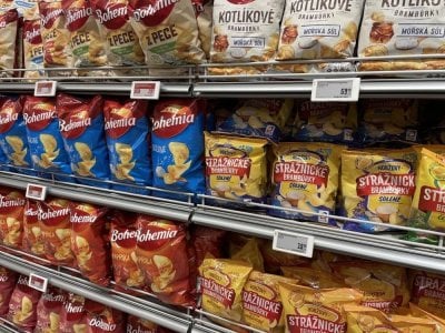 Různá balení brambůrků v regálu supermarketu