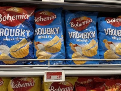 Solené vroubkované brambůrky v regálu supermarketu