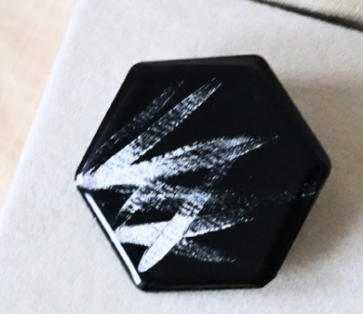 Černá brož ve tvaru hexagonu