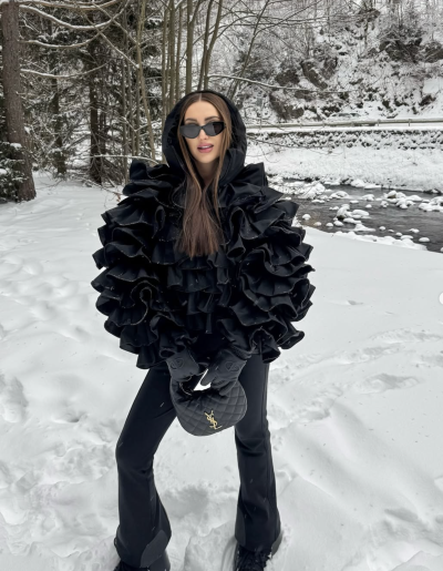 Mladá žena ve stylové černé bundě v zasněžené krajině