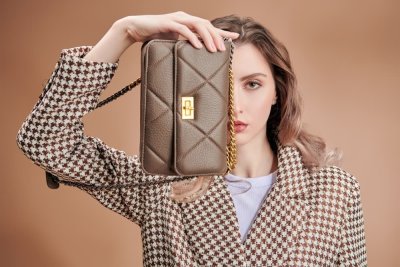 Žena s hnědou kabelkou před obličejem