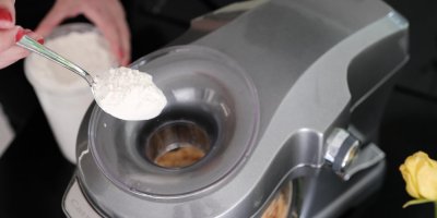 Žena přisypává mouku do kuchyňského robotu s těstem na bramboráky