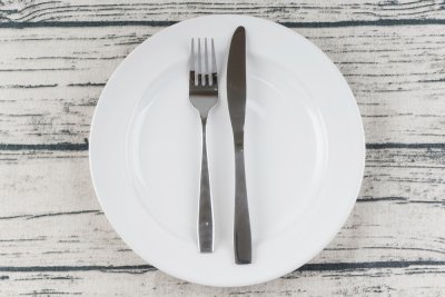 Vidlička a nůž položené vedle sebe na bílém talíři