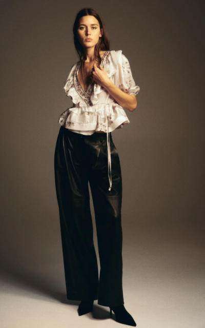 Modelka ve světlém peplum topu a černých kalhotách