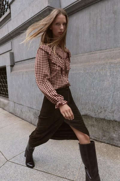 Modelka v kostkované blůze a černé sukni