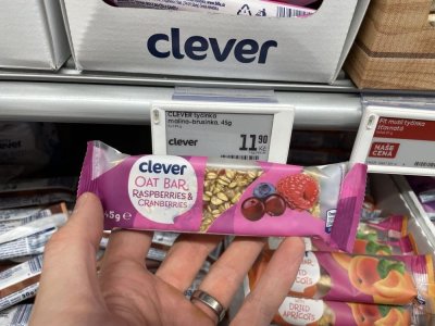 Ruka držící müsli tyčinku před regálem v supermaretu