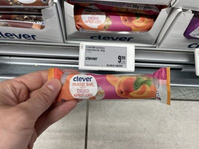 Ruka držící müsli tyčinku před regálem v supermaretu