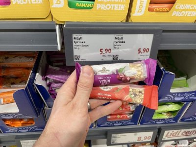 Ruka držící müsli tyčinky před regálem v supermaretu