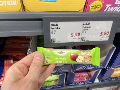 Ruka držící müsli tyčinku před regálem v supermaretu