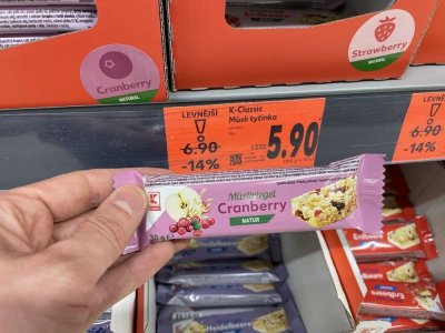 Ruka držící müsli tyčinku před regálem v supermaretu