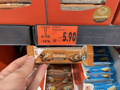 Ruka držící müsli tyčinku před regálem v supermaretu