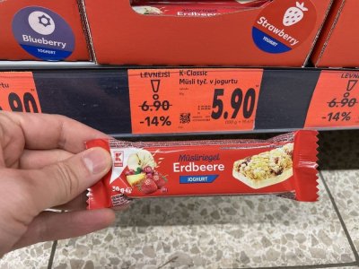 Ruka držící müsli tyčinku před regálem v supermaretu