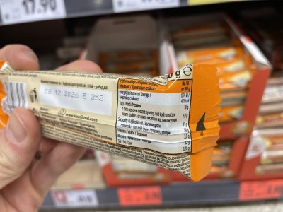 Ruka držící müsli tyčinku před regálem v supermaretu