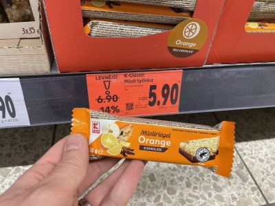 Ruka držící müsli tyčinku před regálem v supermaretu