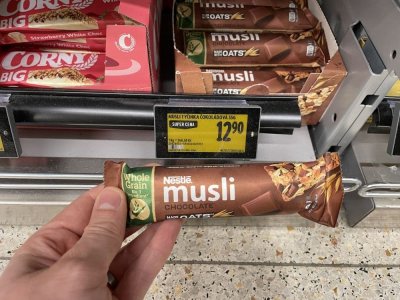 Ruka držící müsli tyčinku před regálem v supermaretu