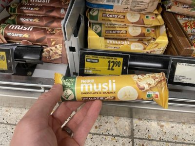 Ruka držící müsli tyčinku před regálem v supermaretu