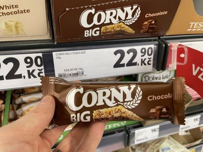 Ruka držící müsli tyčinku před regálem v supermaretu