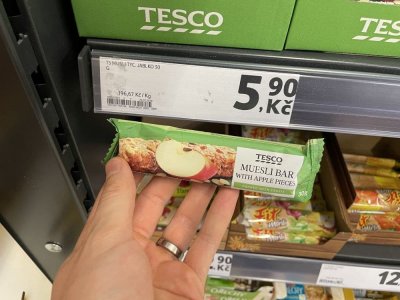 Ruka držící müsli tyčinku před regálem v supermaretu