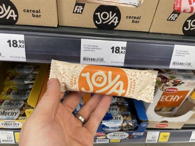 Ruka držící müsli tyčinku před regálem v supermaretu