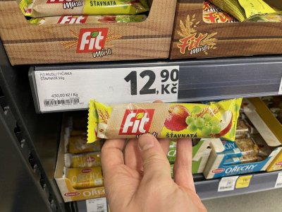 Ruka držící müsli tyčinku před regálem v supermaretu